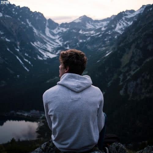 a man sitting on top of a mountain looking at the mountains 