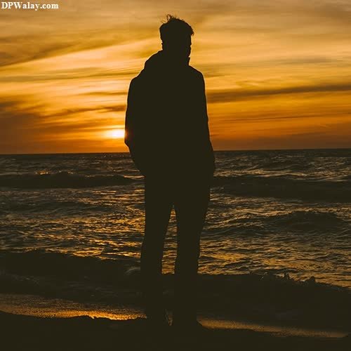 a man standing on the beach watching the sunset