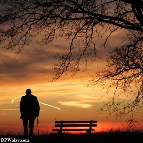 a man standing in front of a bench at sunset