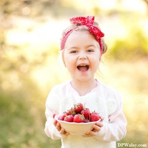 a little girl holding a bowl of strawberries