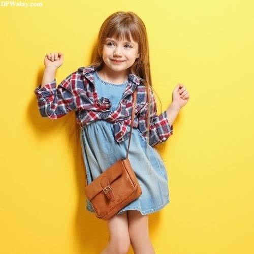a little girl standing against a yellow wall