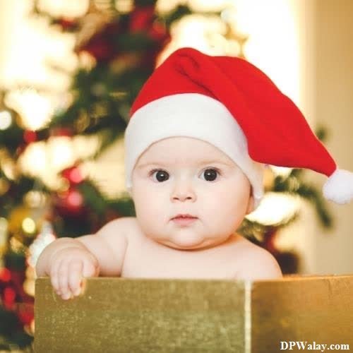 a baby in a santa hat sitting in front of a christmas tree 