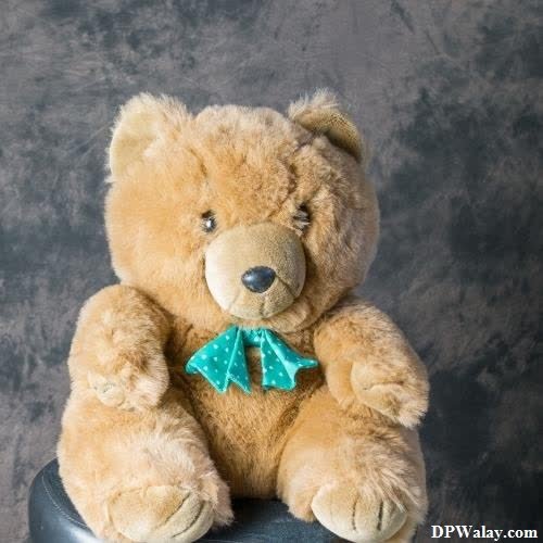 a teddy bear sitting on top of a black chair images by DPwalay