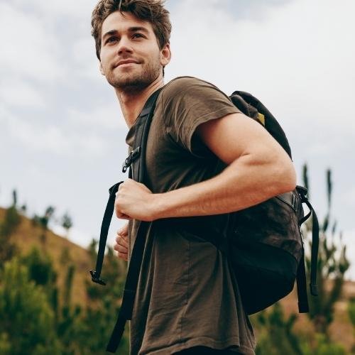 a man with a backpack standing in front of a mountain 