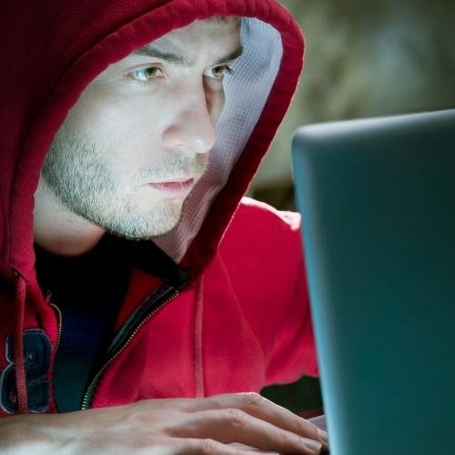 a man in a red hoodie using a laptop