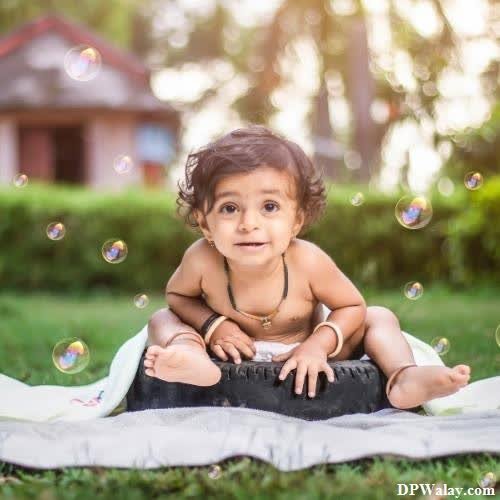 a baby girl sitting on a blanket in the grass