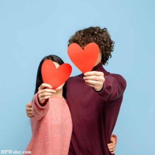 two people holding red paper hearts