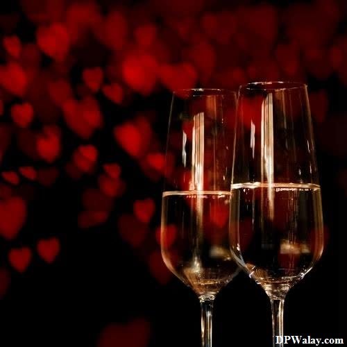 two glasses of champagne on a black background with red hearts