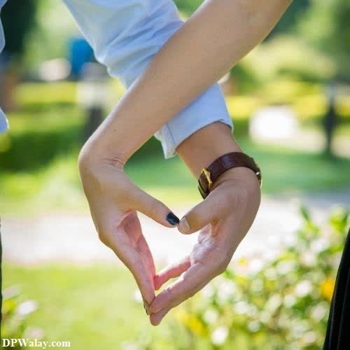 a man and woman holding hands in the shape of a heart