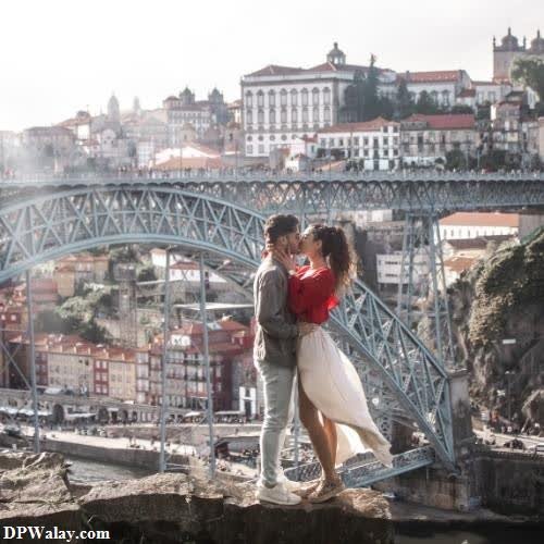 a couple kissing on a bridge over a river 