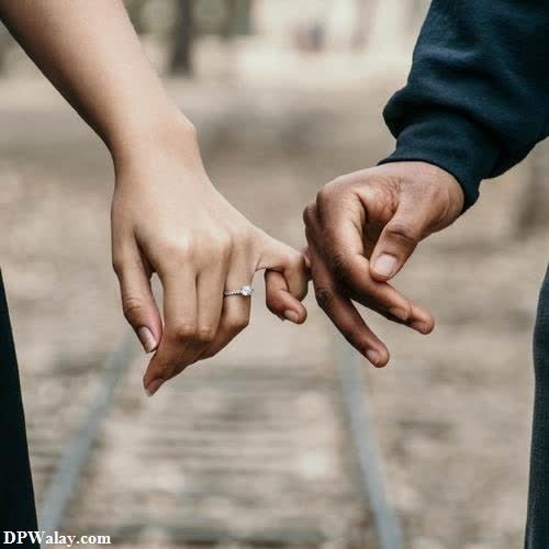 couple dp for whatsapp - a couple holding hands while walking down a train track