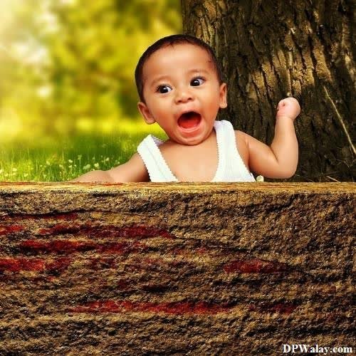 a baby is peeking out from behind a tree