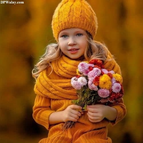 a little girl in a yellow sweater and hat holding flowers 