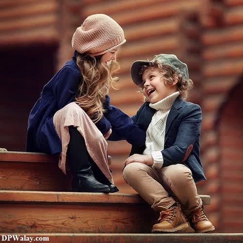 cute whatsapp dp - a little boy and a little girl sitting on a wooden bench
