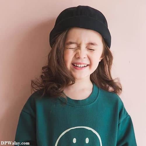 a little girl wearing a green sweater and black hat