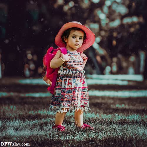 a little girl in a pink hat and dress standing in the grass cute dp images for whatsapp
