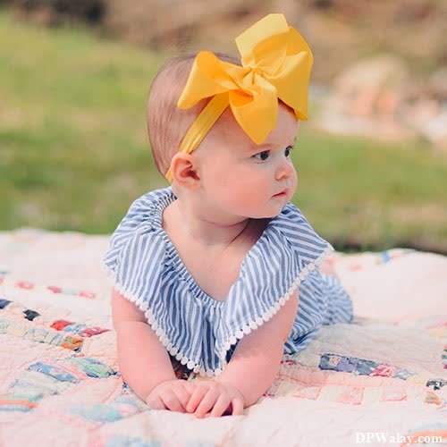 a baby girl wearing a yellow bow on her head 
