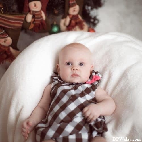 a baby is laying on a blanket next to a christmas tree