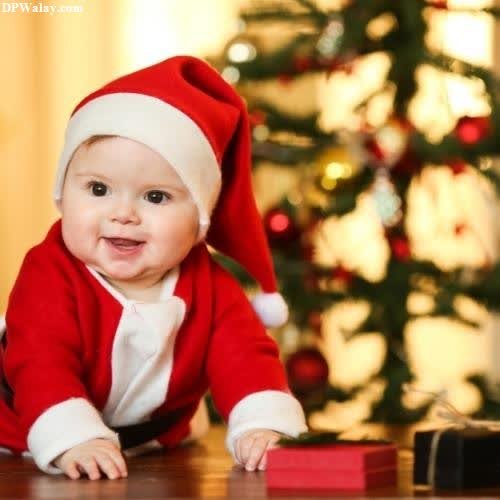 a baby in a santa outfit is laying on the floor