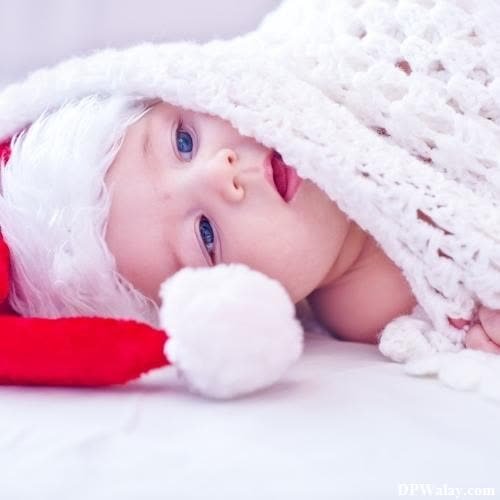 a baby wearing a santa hat and laying on a bed