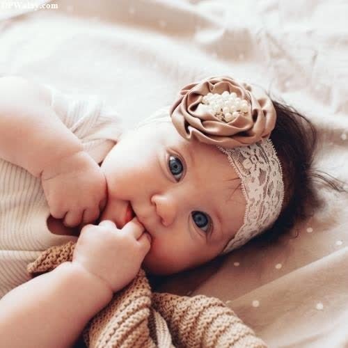 cute whatsapp dp - a baby girl laying on a bed with a knit headband