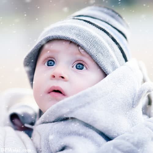 a baby in a winter coat looking up at the camera 