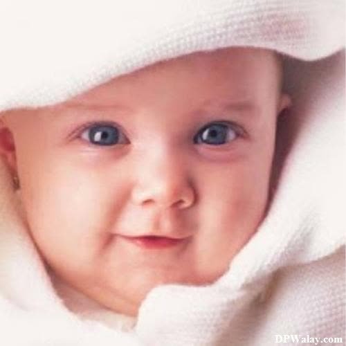 a baby in a white blanket looking at the camera 