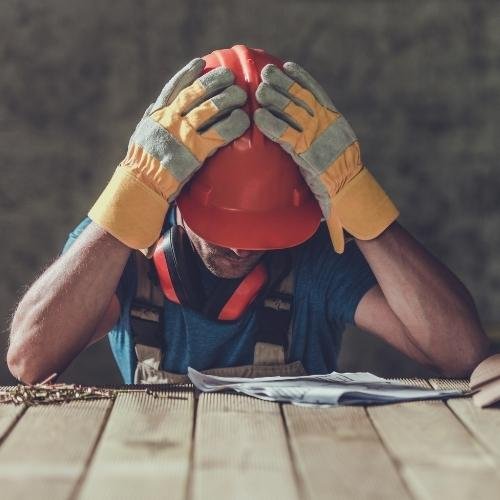 a man in a hard hat and gloves is sitting at a table with a piece of paper