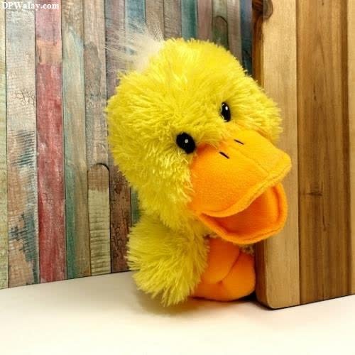 a stuffed duck sitting on top of a wooden shelf 