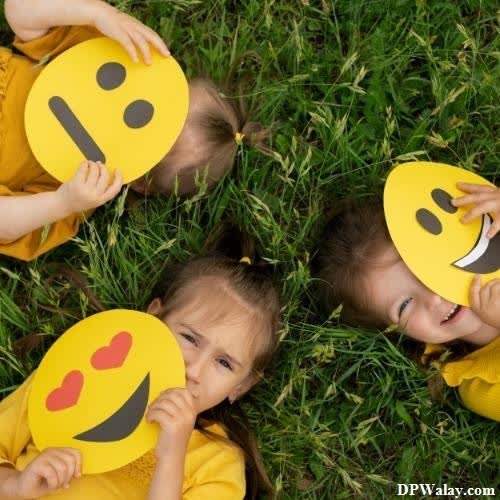 three children in yellow shirts holding up smiley faces good dp