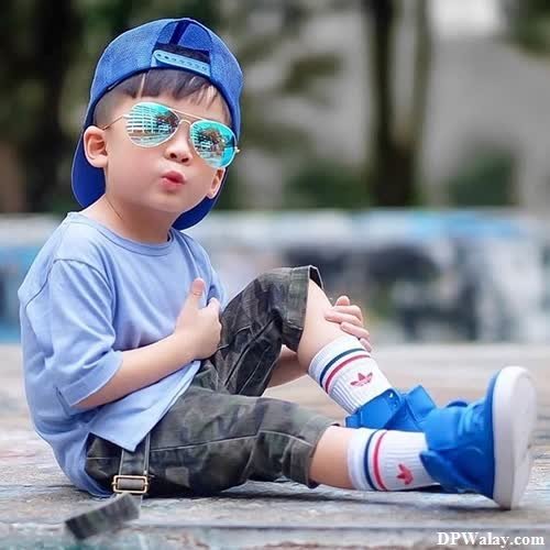 a little boy sitting on the ground wearing sunglasses