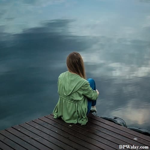 a girl sitting on a dock looking at the water