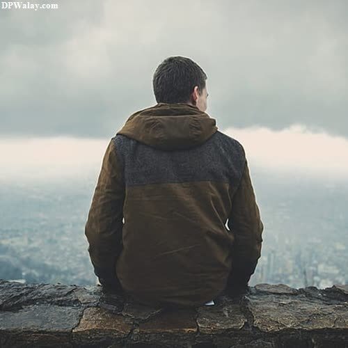 a man sitting on top of a mountain looking out over a city