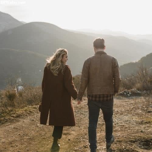 a couple walking down a dirt road holding hands 