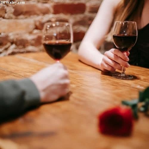 a man and woman sitting at a table with wine glasses love couple whatsapp dp 