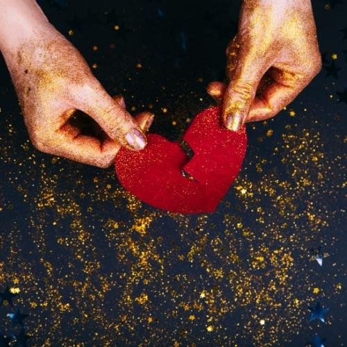 a person holding a red heart in their hands 