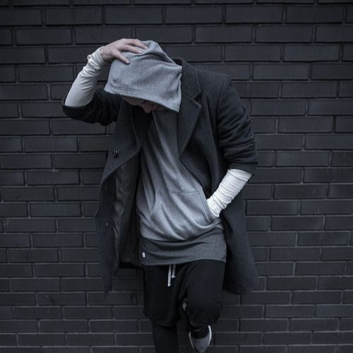 whatsapp dp for boys - a man standing against a brick wall wearing a grey hoodie