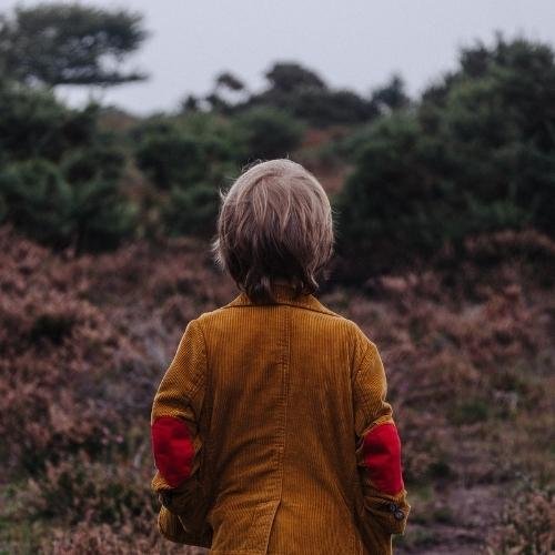 a little boy walking down a path in the woods