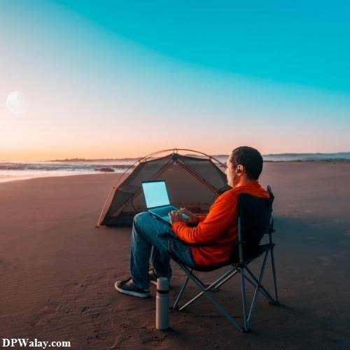 a man sitting in a chair on the beach with a laptop