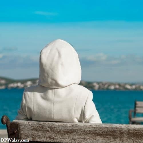 a child sitting on a bench looking out at the ocean