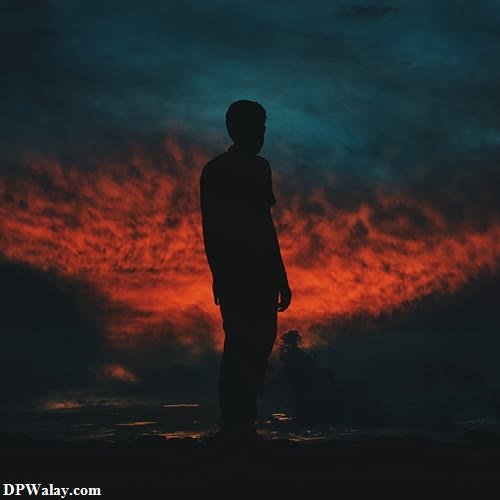 a man standing in the dark with a red sky behind him 