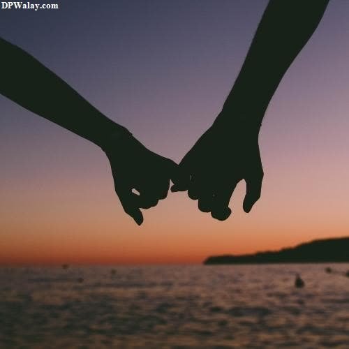 two people holding hands with the sunset in the background