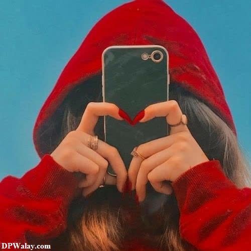 hidden face dp for girls - a woman in a red hoodie holding a phone