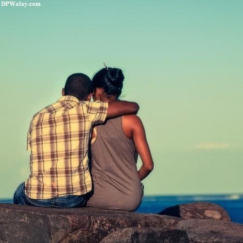 unique dp for whatsapp - a couple sitting on a rock looking out at the ocean
