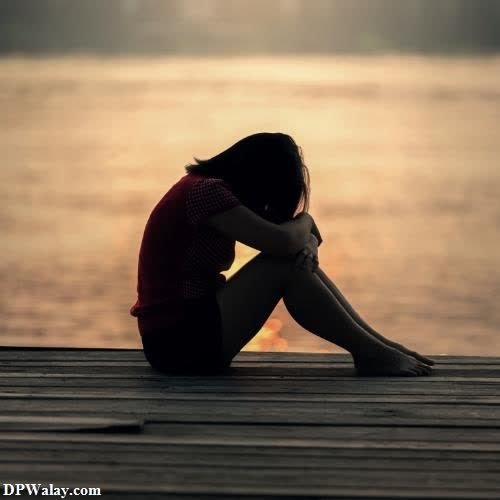 sad woman sitting on the pier at sunset