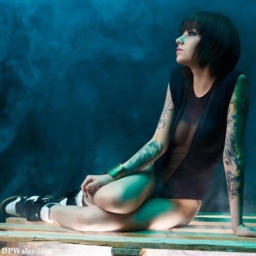 a woman sitting on a wooden bench with a tattoo on her arm
