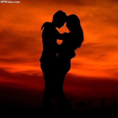a silhouette of a couple kissing in front of a sunset