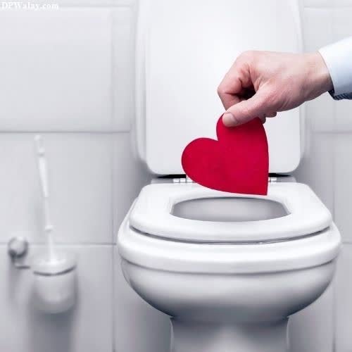 a person putting a red heart in the toilet