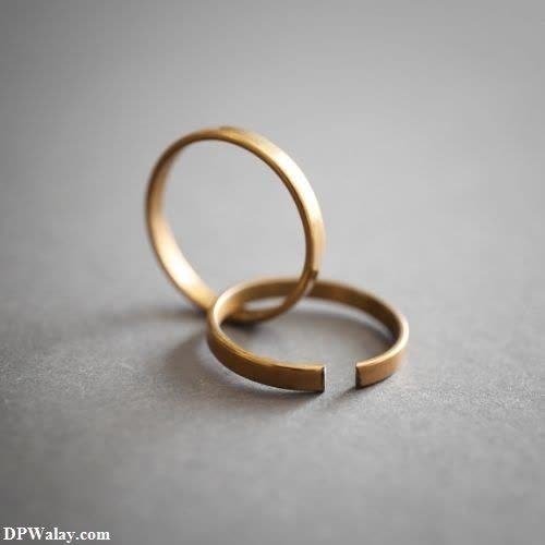 a gold wedding ring on a grey surface images by DPwalay