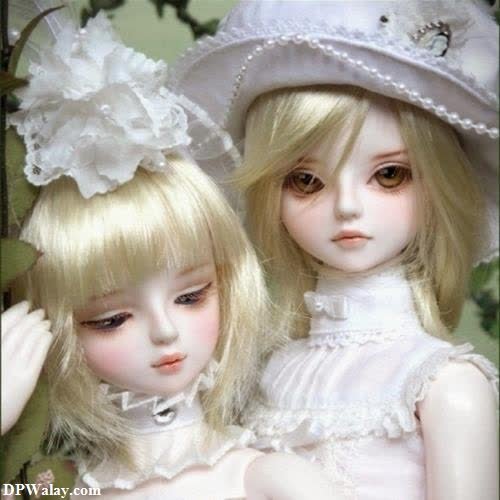 two dolls are dressed in white dresses and hats
